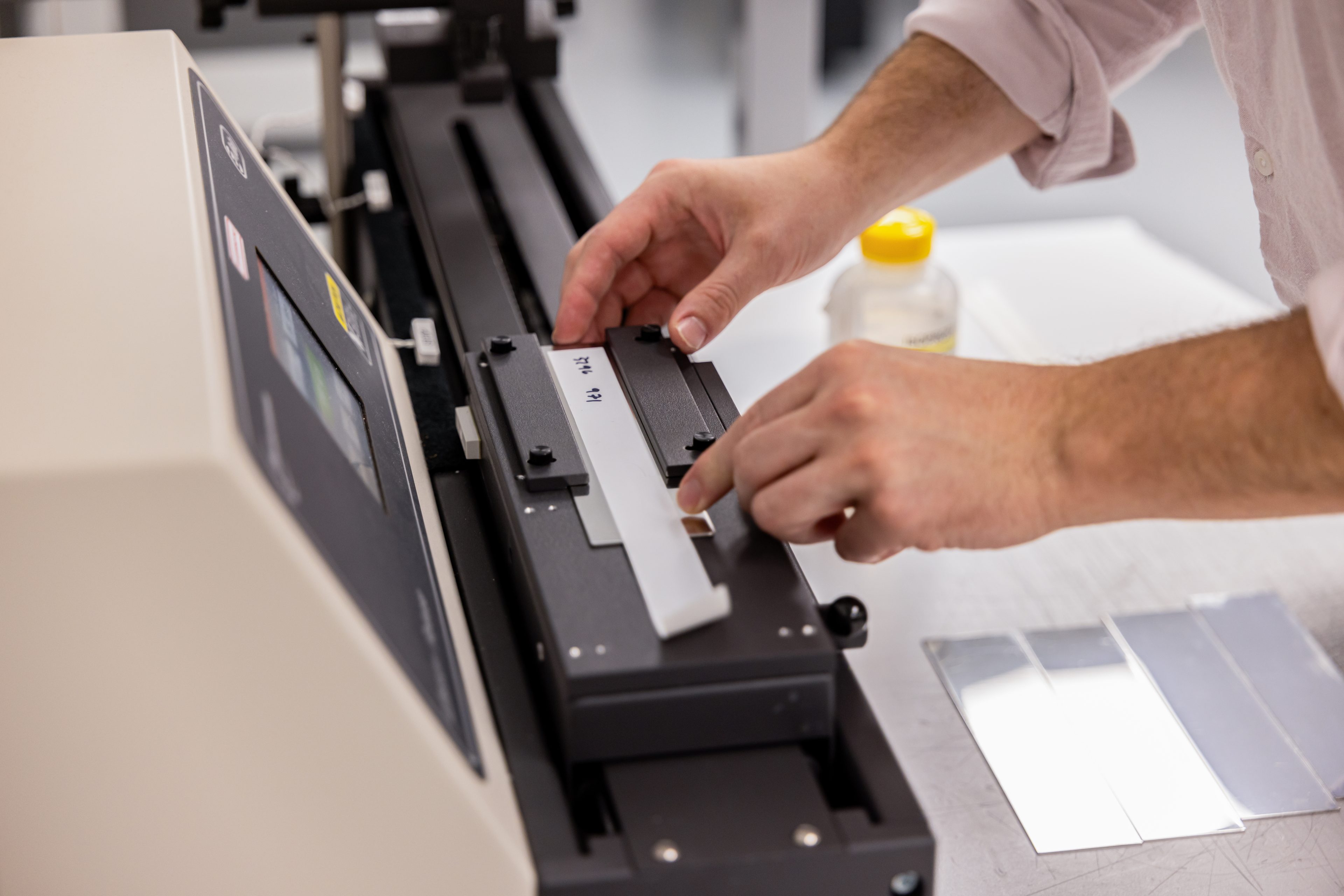 Hands positioning a label sample for adhesive testing