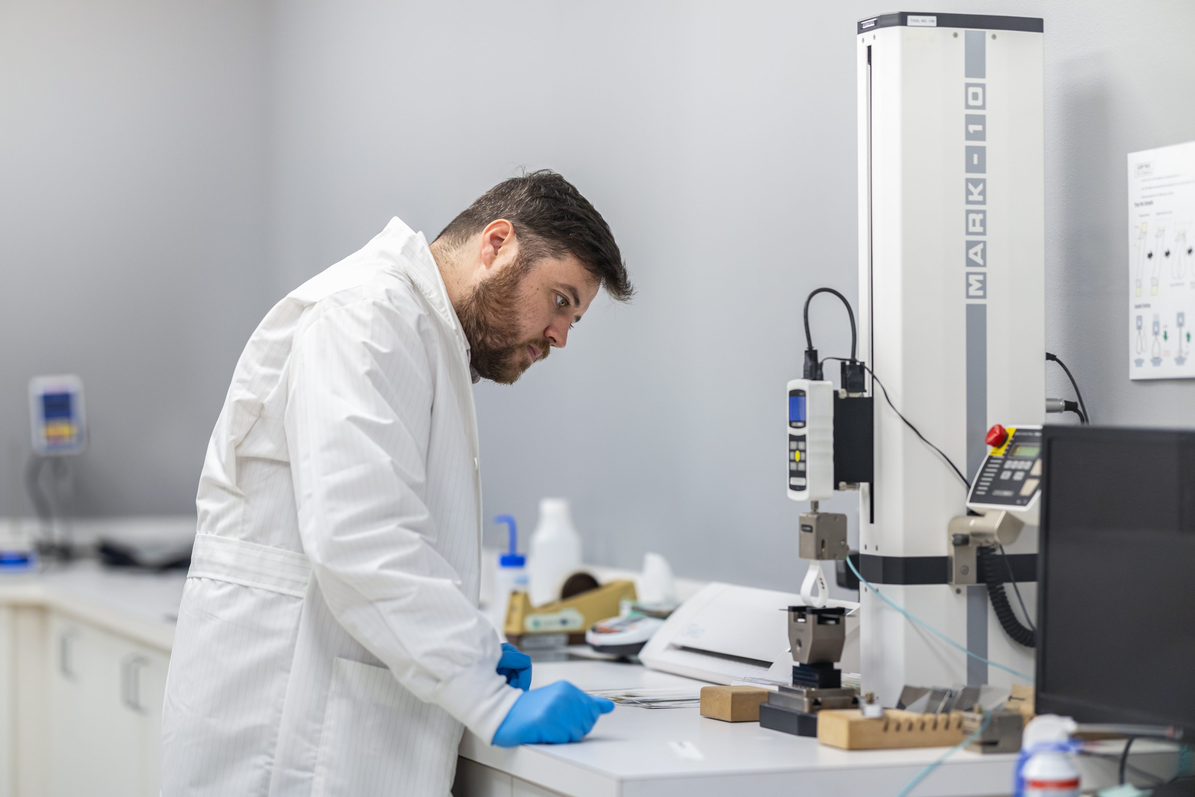 CleanMark technician using a tension testing instrument to evaluate label materials